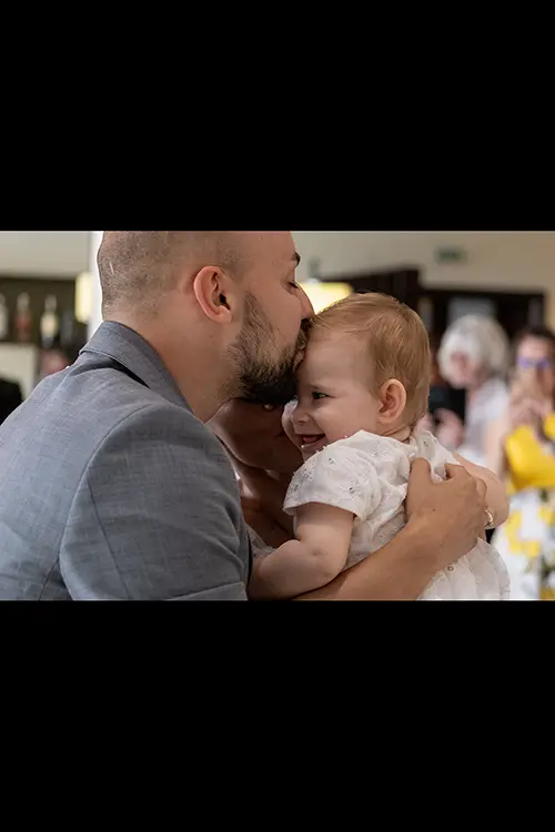 Color wedding photo by Lucas Georgiev. Newlyweds kissing a baby. Place: Lovech, Bulgaria