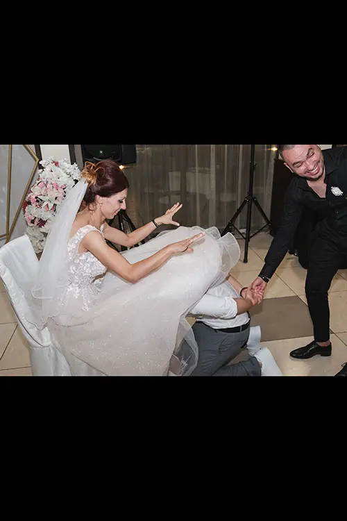 Color wedding photo by Lucas Georgiev. Groom pulls on the garter. Place: Lovech, Bulgaria