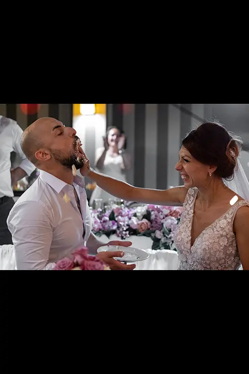 Color wedding photo by Lucas Georgiev. Bride smash a piece of cake on the groom's face. Place: Lovech, Bulgaria